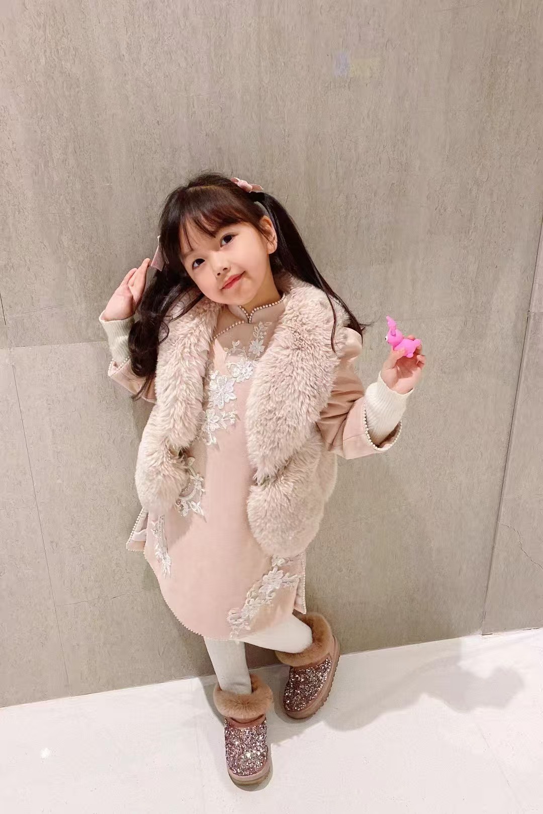 一位穿浅粉色礼服与毛绒马甲的女孩